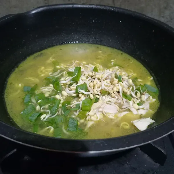 Masukkan suiran ayam, tauge, dan daun bawang yang sudah diiris ke dalam kuah soto.