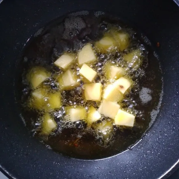 Kupas kentang, potong dadu, cuci bersih. Lalu goreng sampai kuning kecokelatan. Angkat dan sisihkan.