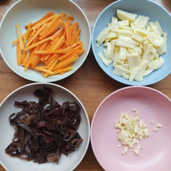 Cincang bawang putih dan iris jamur kuping, wortel, dan tofu seperti korek
