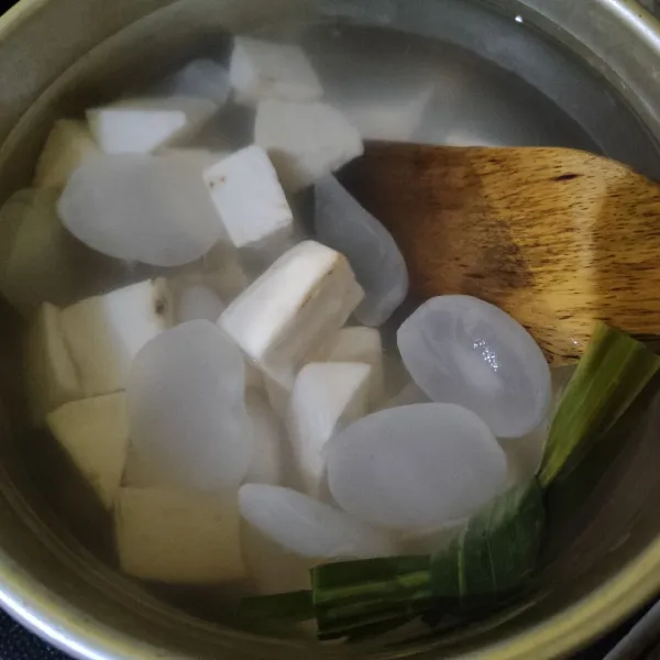 Didihkan air bersama daun pandan, masukkan ubi dan kolang kaling. Rebus hingga setengah matang.