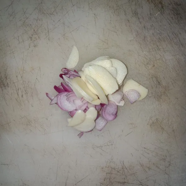 Siangi bawang merah dan bawang putih kemudian iris tipis-tipis