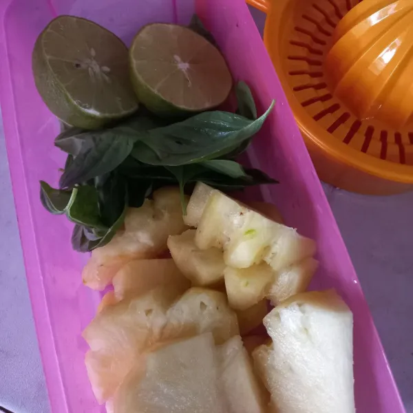 Siapkan bahan-bahan dengan membersihkan nanas, petiki daun kemangi, dan potong bagi dua lemon.