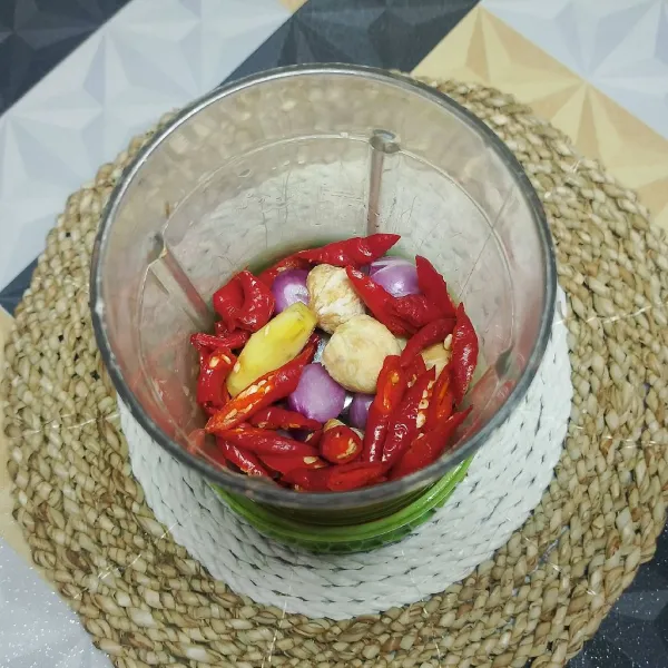 Haluskan bawang merah, bawang putih, kemiri sangrai, jahe, dan 50 gram cabe merah.