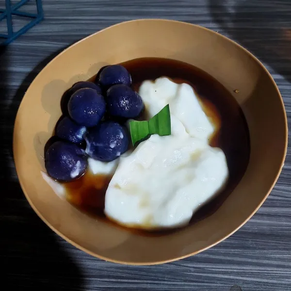 Letakan bubur sumsum dalam mangkuk saji, beri bola ungu dan siram dengan kuah kinca