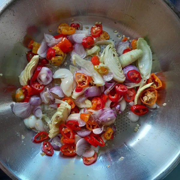 Kurangi minyak dalam wajan. Kemudian masukkan bawang bombay, cabai merah besar, cabai rawit merah, bawang merah dan bawang putih yang sudah di iris. Tumis hingga layu.
