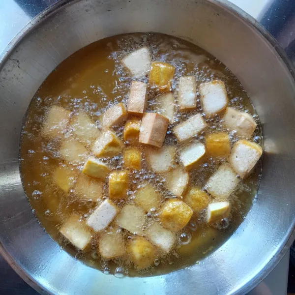 Panaskan secukupnya minyak dalam wajan. Masukkan tahu dan goreng hingga tahu matang kuning kecokelatan. Angkat dan sisihkan.