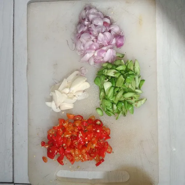 Iris-iris bawang putih, bawang merah, cabai rawit, dan petai