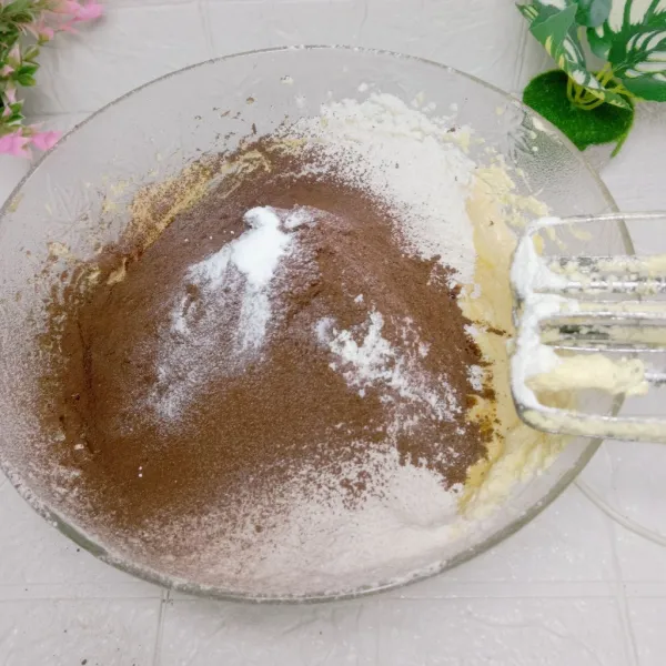 Kemudian masukkan dan saring tepung terigu, coklat bubuk, baking, garam dan vanile. Mixer kembali dengan kecepatan rendah sampai tercampur merata