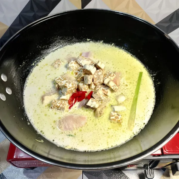 Masukkan pelengkap, tempe dan irisan cabai merah, masak dengan api kecil sambil agar santan tidak pecah, masak sampai ayam empuk, angkat dan sajikan bersama ketupat.