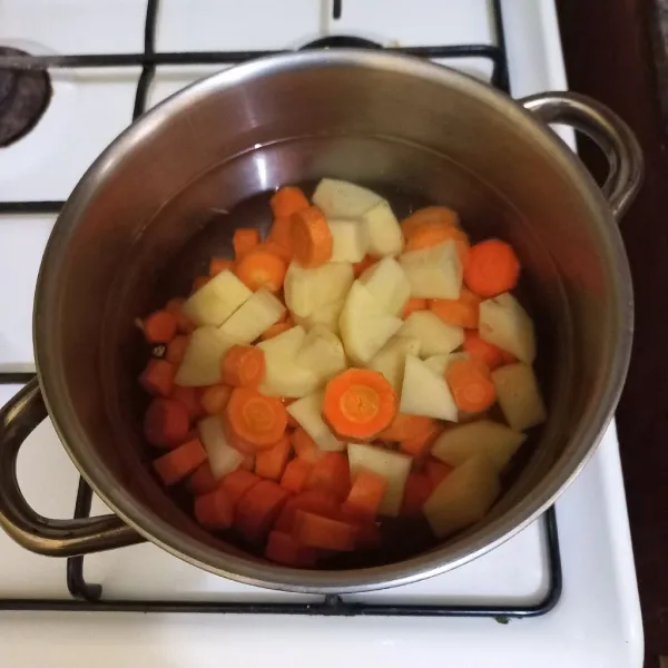 Didihkan air masukan potongan wortel dan kentang masak hingga setengah matang
