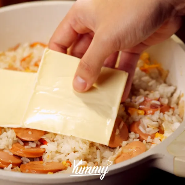 Tambahkan 2 lembar keju slice ke atas nasi dan sosis Kanzler Singles Keju 2X, tutup pan agar keju meleleh.