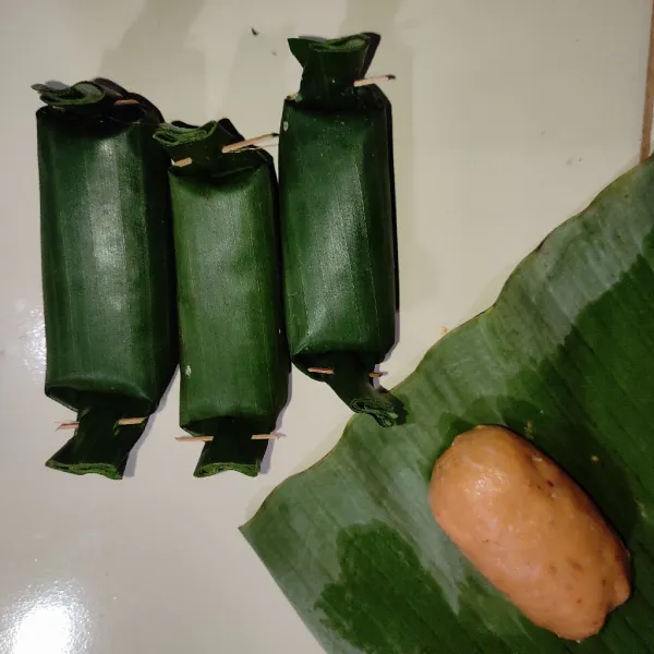 Ambil sebagian adonan lalu bentuk bulat dan bungkus dengan daun pisang.