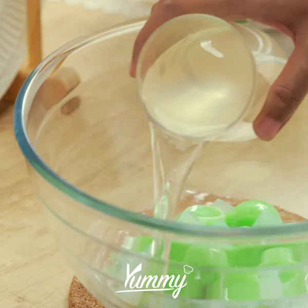 Campur jelly pandan berbentuk bulat, susu kental manis, susu evaporasi, air kelapa, dan nata de coco di dalam bowl.