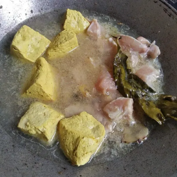 Masukkan potongan dada ayam dan tahu. Aduk dan tambahkan air, garam dan kaldu bubuk. Masak sampai air mendidih.