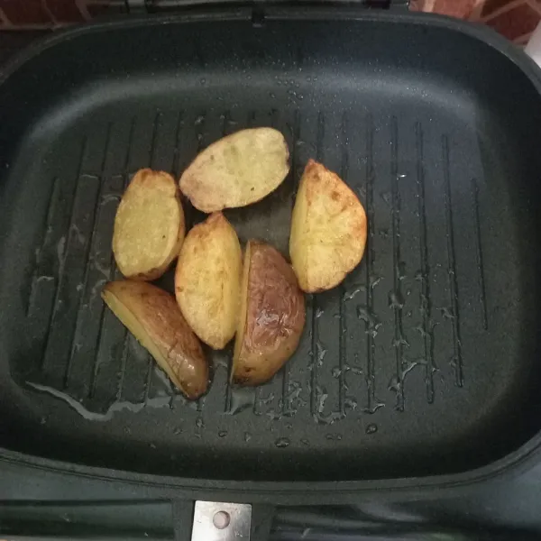 Potong kentang berbentuk wedges lalu panggang di wajan teflon, oleskan mentega dan tambahkan sedikit minyak, gunakan api kecil.
