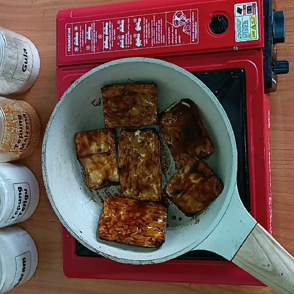 Bakar tempe di teflon tanpa minyak sama sekali ya. Masak hingga matang.