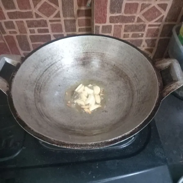 Panaskan minyak goreng untuk menumis bawang putih sampai harum dan keemasan, lalu masukkan terasi.