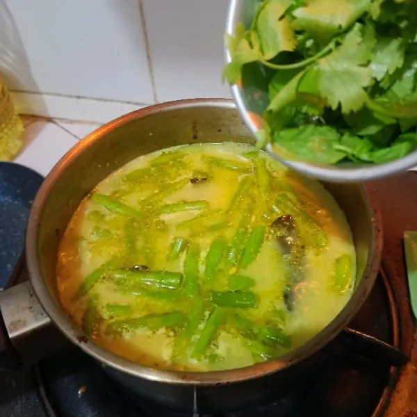 Tambahkan santan, daun ketumbar dan daun kemangi. Aduk rata. Masak hingga mendidih. Matikan api dan sajikan bersama jeruk limau/nipis