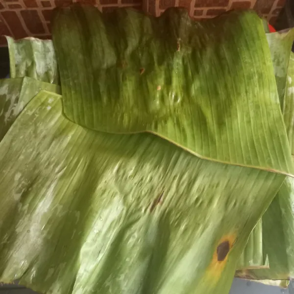 Cuci bersih daun pisang, buang tulang daunnya lalu panggang sampai layu agar mudah dibentuk.