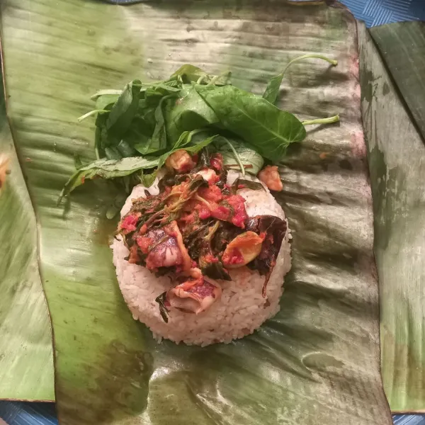 Bentuk nasi dengan mangkuk kecil, tata diatas daun pisang, tambahkan lauk cumi dan sayur kangkung.