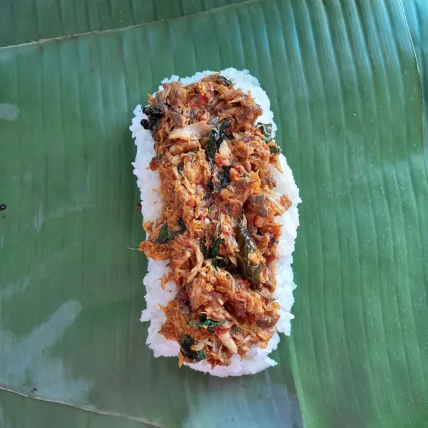 Membungkus : Siapkan 1-2 lembar daun pisang, beri secukupnya nasi gurih. Kemudian taruh ikan suwir berbumbu di atas nasi gurih.