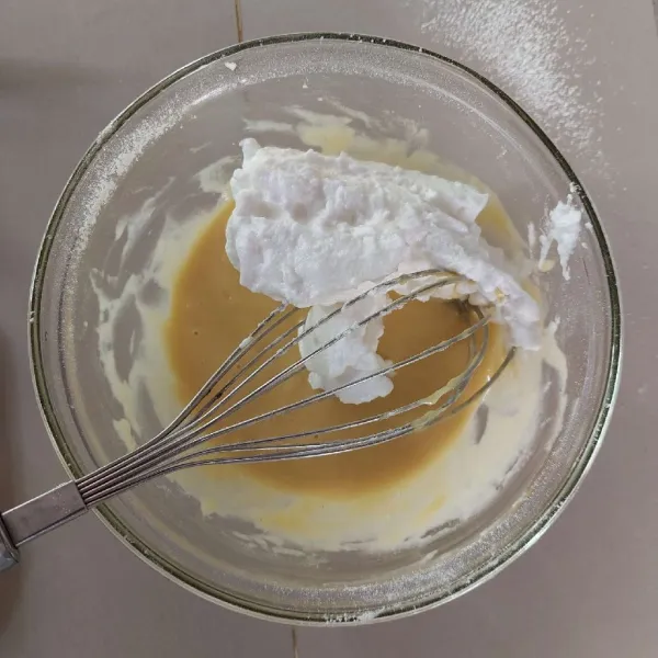 Tambahkan adonan putih telur ke adonan kuning bertahap, aduk hingga tercampur rata.