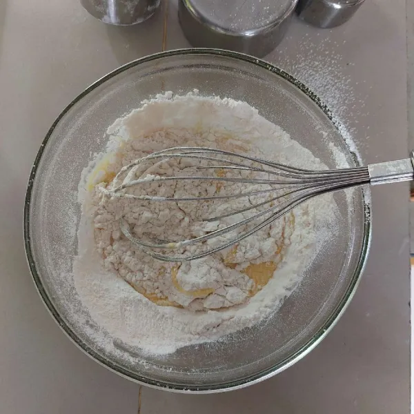 Ayak tepung dan baking powder, tambahkan ke adonan kuning telur, aduk menggunakan wish hingga tercampur rata