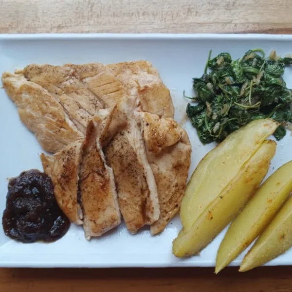 Tata ayam, kentang, bayam di atas piring. Beri bumbu lada hitam untuk cocolan.