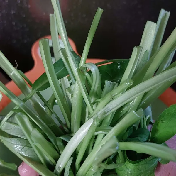 Potong bagian bawah kangkung dekat akar, cuci bersih, lalu belah dua.