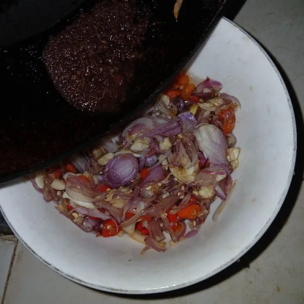 Panaskan minyak, masukkan terasi, goreng sambil terasinya dihancurkan. Matika  api. Kemudian selagi minyaknya panas tuang kedalam mangkuk yang berisi bahan sambal tadi. Aduk rata.