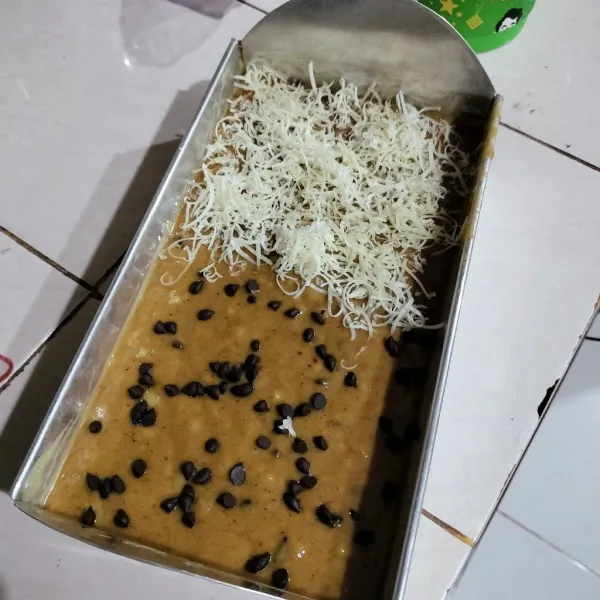 Siapkan loyang ,olesi dengan mentega lalu tuang adonan, taburi kembali atasnya dengan chococips dan parutan keju optional sesuai selera.