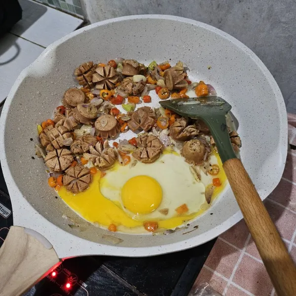 Sisihkan osis kepinggir wajan, masukkan telur, buat orak arik.