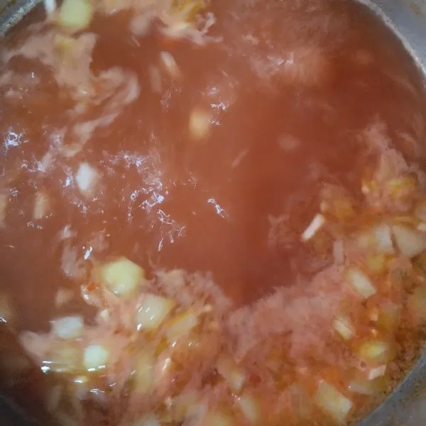 Kemudian tuang jus tomat pada tumisan bawang, masak hingga mendidih.