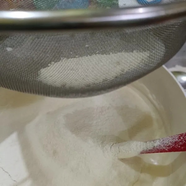 Kemudian masukkan tepung terigu, susu bubuk, baking powder dan garam, sambil diayak dan aduk rata dengan spatula