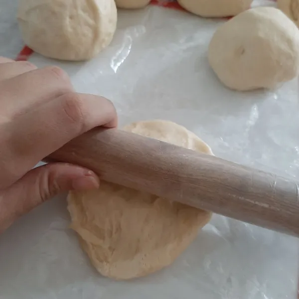 Ambil adonan lalu pipihkan, keluarkan udaranya dengan menggunakan tangan. Lalu gilas tipis. Taburi bagian atasnya dengan tepung lagi agar tidak lengket ketika di tumpuk dengan yang lain. Lakukan hingga adonan habis.