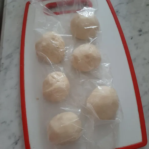 Bagi adonan jadi 6  bulatkan dan tutup dengan plastik.  Proofing lagi untuk ke 2x nya selama 15-20 menit. Agar adonan tidak lengket saat di bulatkan taburi area kerja dengan terigu, tipis tipis saja.