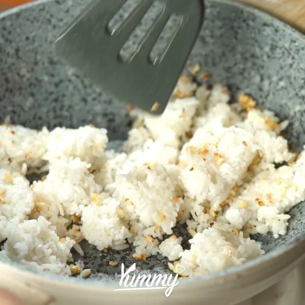Masukkan nasi, kaldu jamur, dan lada putih. Aduk hingga merata.