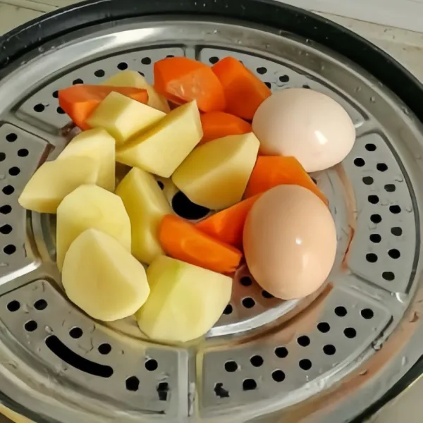 Potong-potong kentang dan wortel menjadi beberapa bagian lalu kukus dengan telur