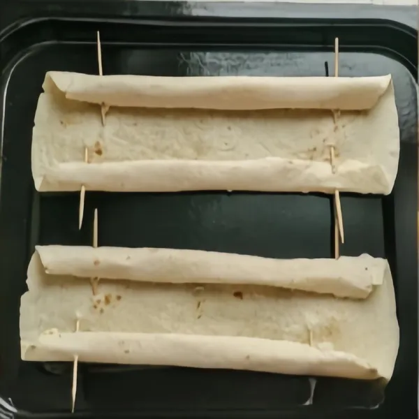 Gulung kedua sisi tortilla dan kencangkan dengan tusuk gigi