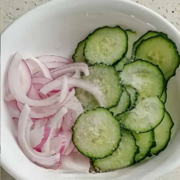 Iris tipis mentimun dan bawang bombay lalu campurkan dengan garam, kemudian peras airnya