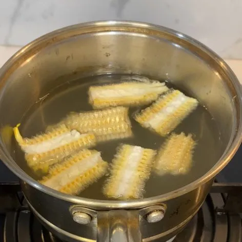 Rebus bonggol jagung, biarkan mendidih beberapa saat lalu keluarkan bonggol jagungnya.