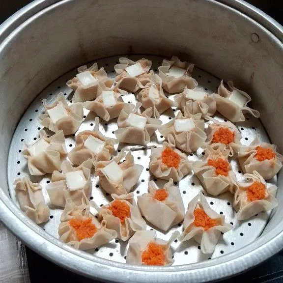 Isi kulit dimsum dengan adonan, kemudian beri toping wortel parut dan keju lembar yang sudah dipotong kotak-kotak, kukus selama 30 menit, dimsum ayam siap disajikan