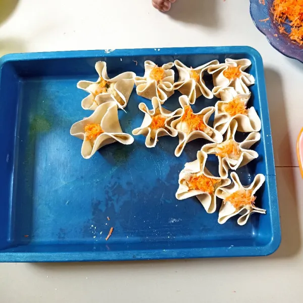 Bungkus adonan dengan kulit dimsum, beri topping wortel parut, lakukan sampai adonan habis.