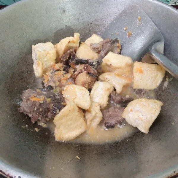 Tuang secara air, masukkan daging dan tahu goreng. Aduk rata.