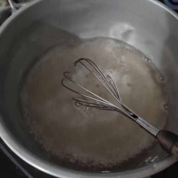 Membuat puding bening, campur gula, air dan setengah bungkus agar aduk rata, nyalakan kompor masak hingga mendidih sambil di aduk