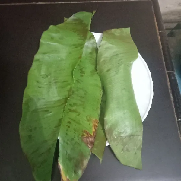 Cuci bersih daun pisang, buang bagian tengahnya lalu bakar sampai layu.