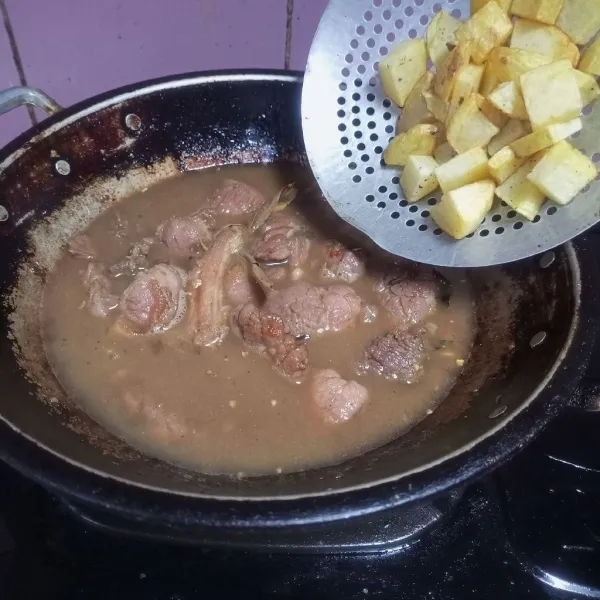 Masukkan kentang, kecilkan api, masak hingga daging matang dan kuah mengental.