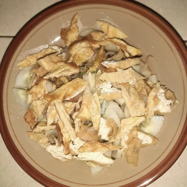 Dalam piring, tata lontong, toge, timun yang dicacah, tahu potong-potong, telur dadar yang dipotong-potong, lalu beri sambal kacang.