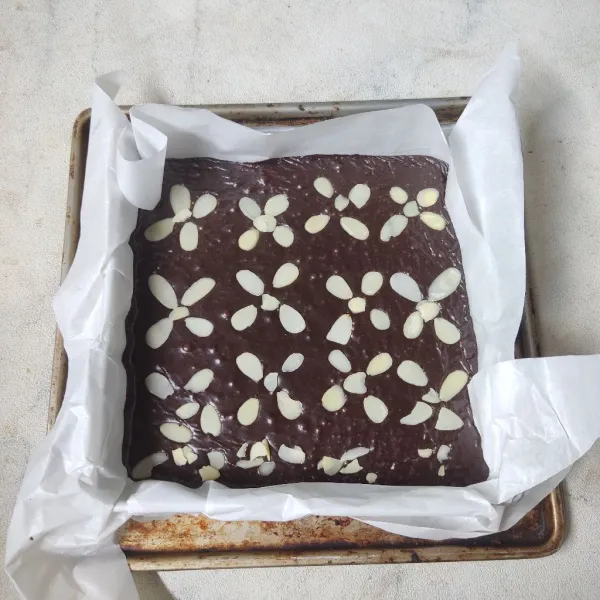 Siapkan loyang ukuran 20x20 cm yang telah dialasi kertas roti. Masukkan adonan brownies. Beri topping almond slices. Diamkan dahulu kisaran 10 menit.