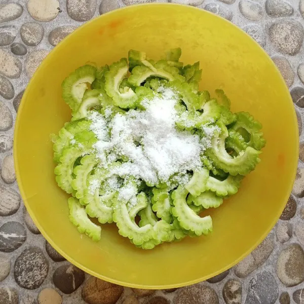 Tambahkan garam kemudian remas-remas pare hingga berair, kemudian bilas dengan air dan bilas